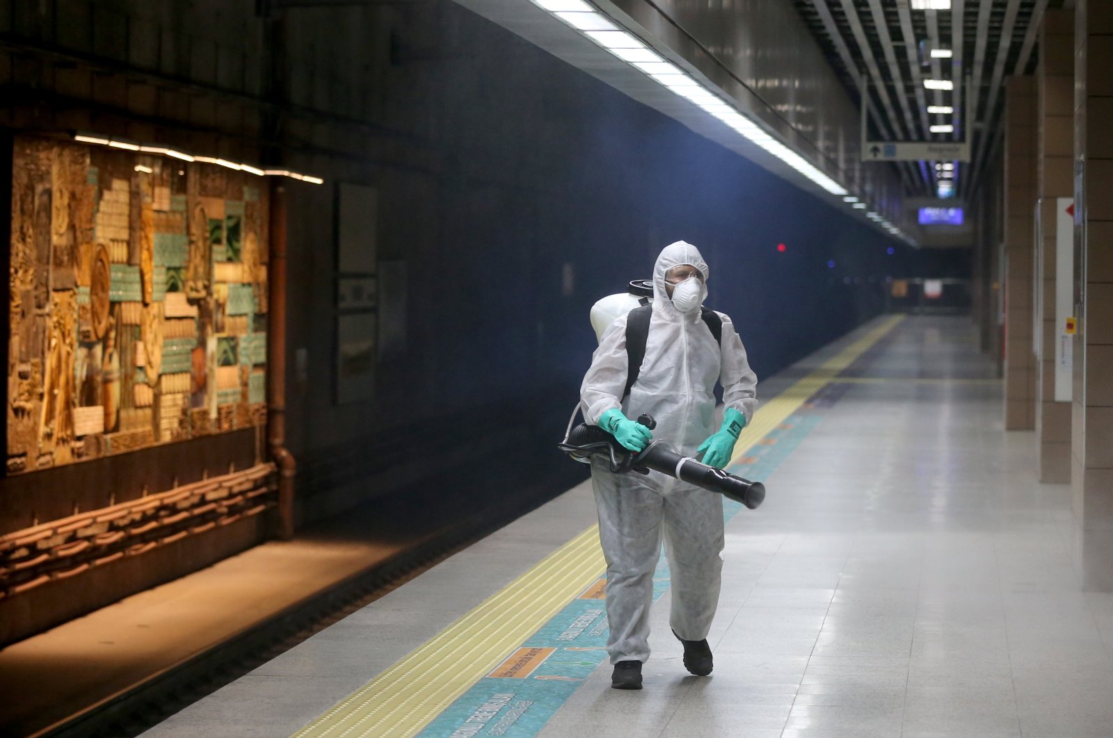 A worker sprays disinfectant at a station of the Marmaray underwater rail line, which connects Istanbul's Asian and European sides, Mar. 6, 2020. (AA Photo)
