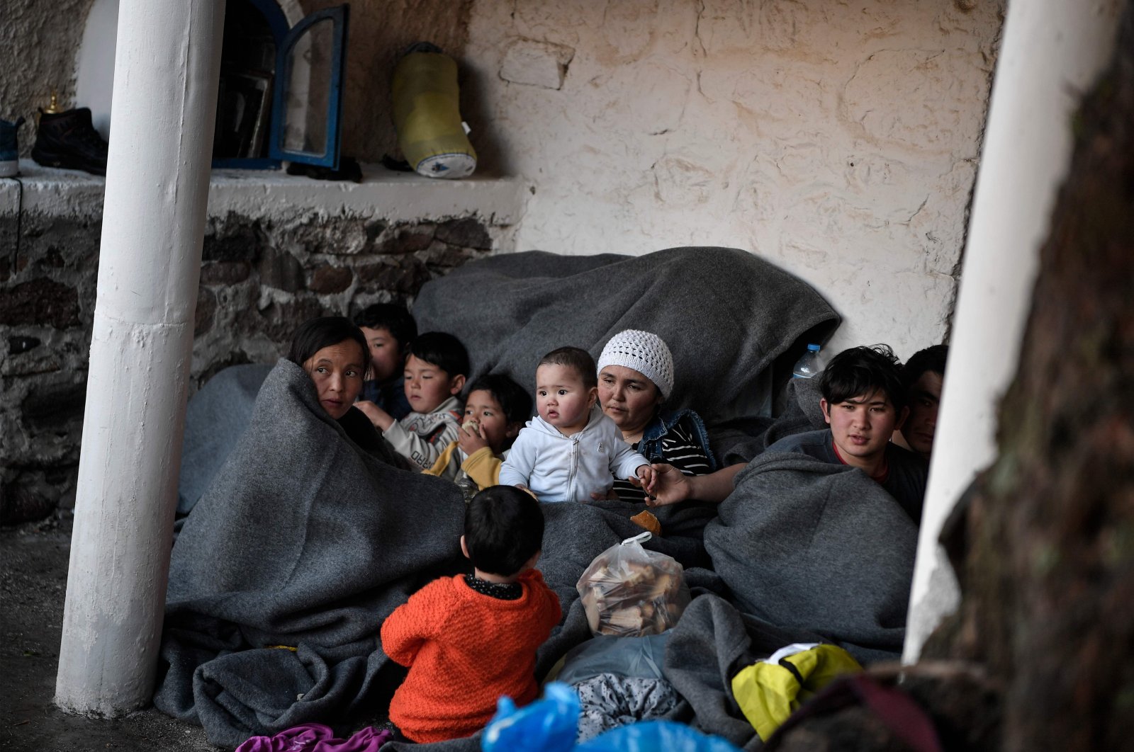 Migrants and refugess who arrived from Turkey to the Greek island of Lesbos on March 5, try to keep warm as they gather in the yard of a small church where they have spent the rainy night near Skala Sykamnias on March 6, 2020. (AFP Photo)