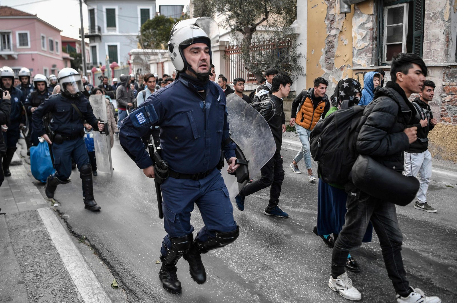 Greek anti-riot police run after migrants and refugees from the Moria camp who gathered outside the port of Mytilene on the island of Lesbos, hoping to get a ferry to Athens, on March 4, 2020. (AFP Photo)