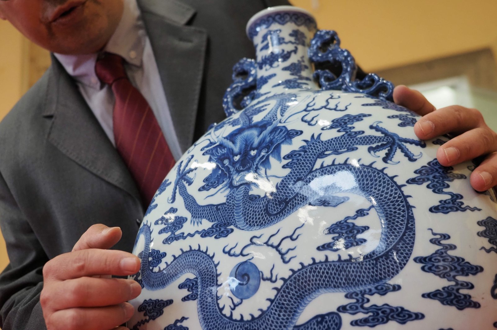 Auctioneer Olivier Clair presents a rare blue, white and celadon porcelain moon flask with a dragon belonging to the 18th century's emperor Qianlong on March 7, 2020 at the Palais Jacques Coeur in Bourges. (AFP Photo)