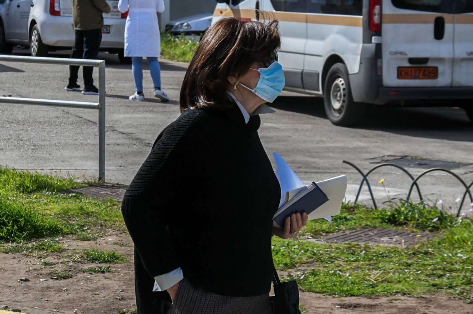 A woman wearing a protective face mask walks in front of the Patras University Hospital in Rio, outside Patras, southwestern Greece, where three patients infected with COVID-19, the new coronavirus, are hopitalised. 