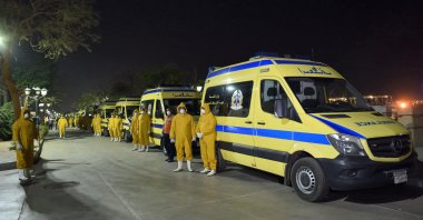 Egyptian health ministry emergency responders stand next to ambulances ready on the scene to transport suspected COVID-19 coronavirus disease cases that were detected on a Nile cruise ship, in the southern city of Luxor late on March 7, 2020. (AFP Photo)