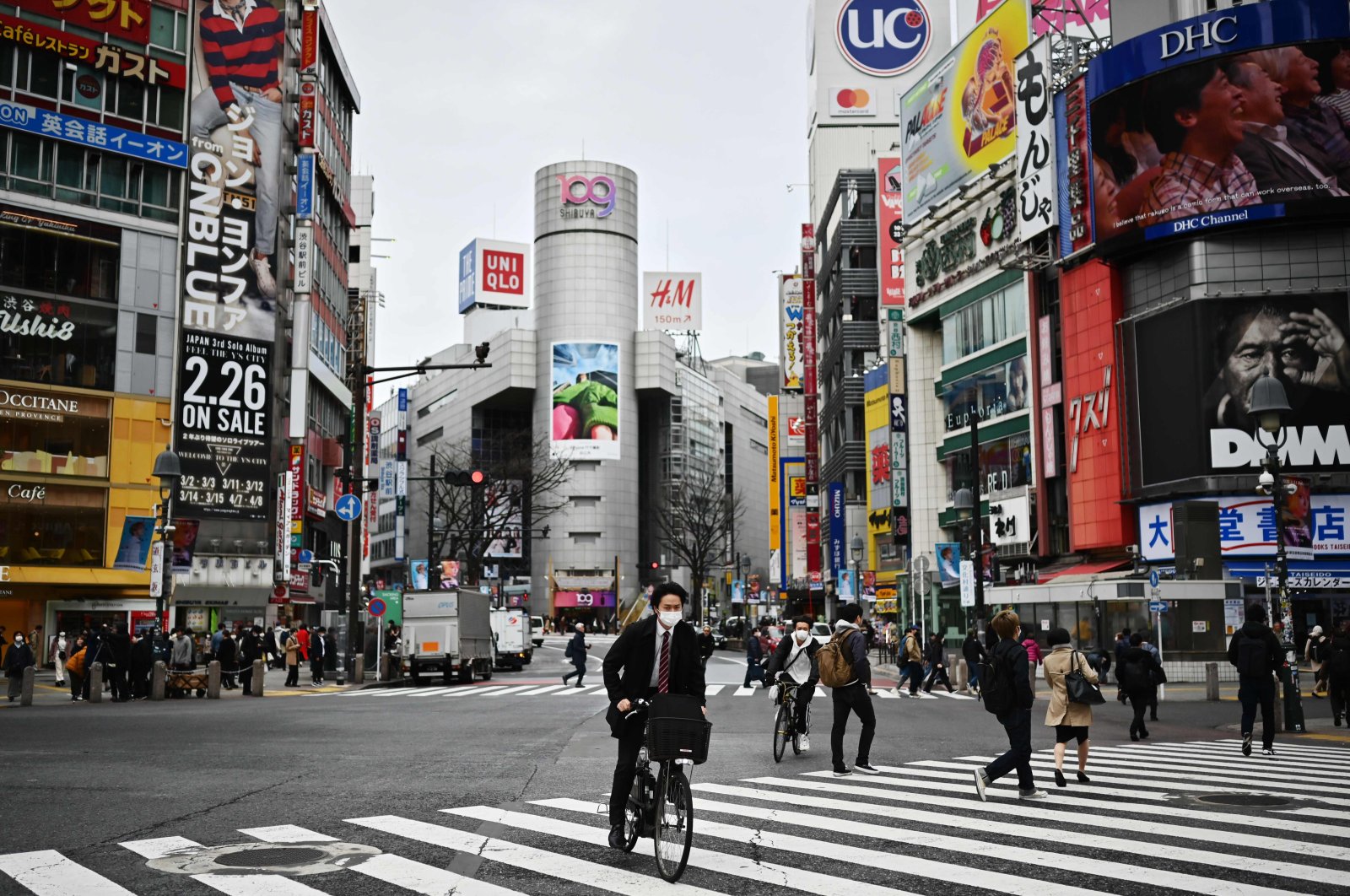 Man wearing a face mask rides a bicycle across a zebra crossing in Shibuya district, Tokyo, March 9, 2020. (AFP Photo)