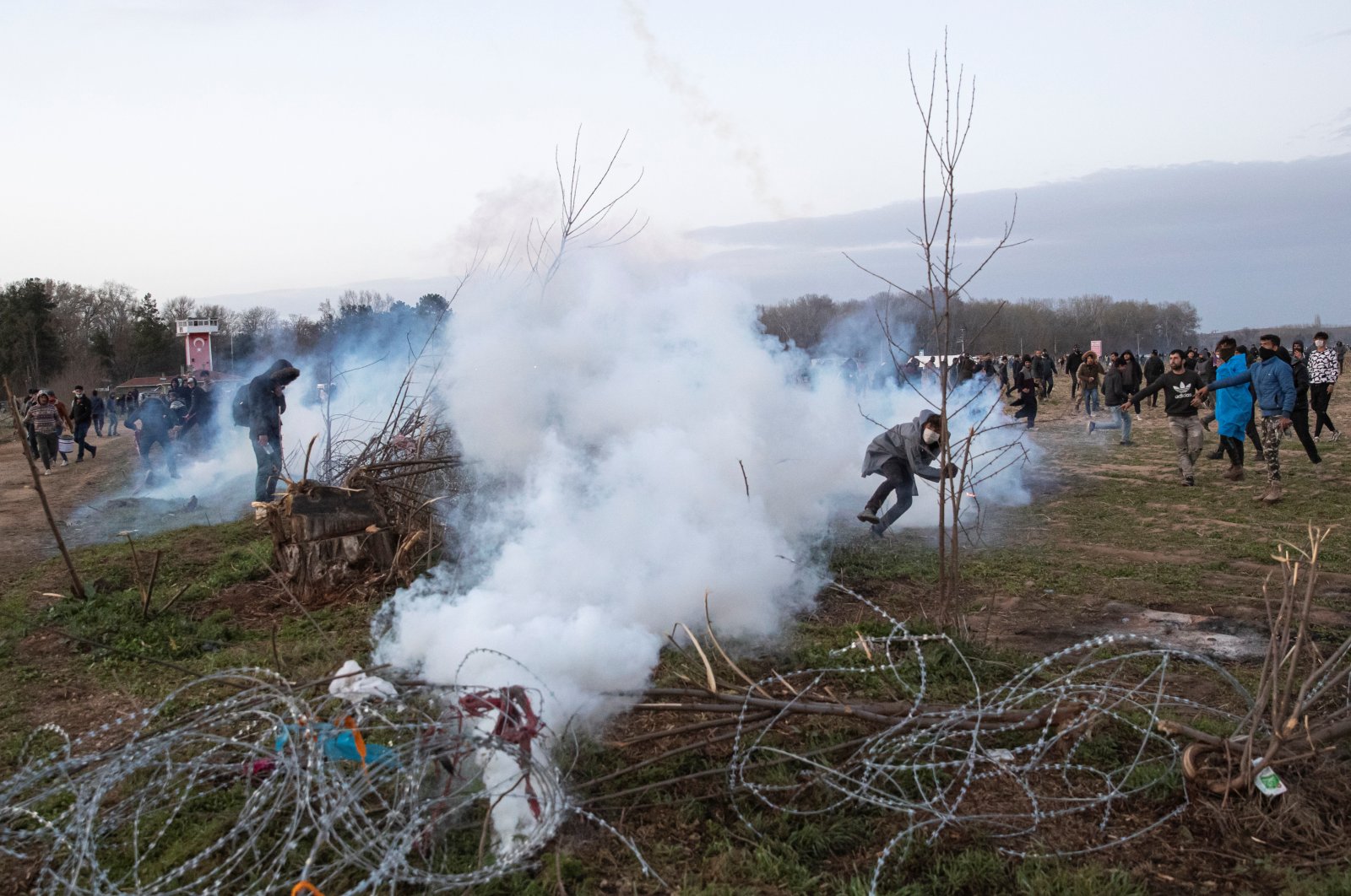 A migrant throws back a tear gas canister as they clash with Greek riot police on the Turkish-Greek border near Turkey's Pazarkule border crossing with Greece's Kastanies, March 7. REUTERS