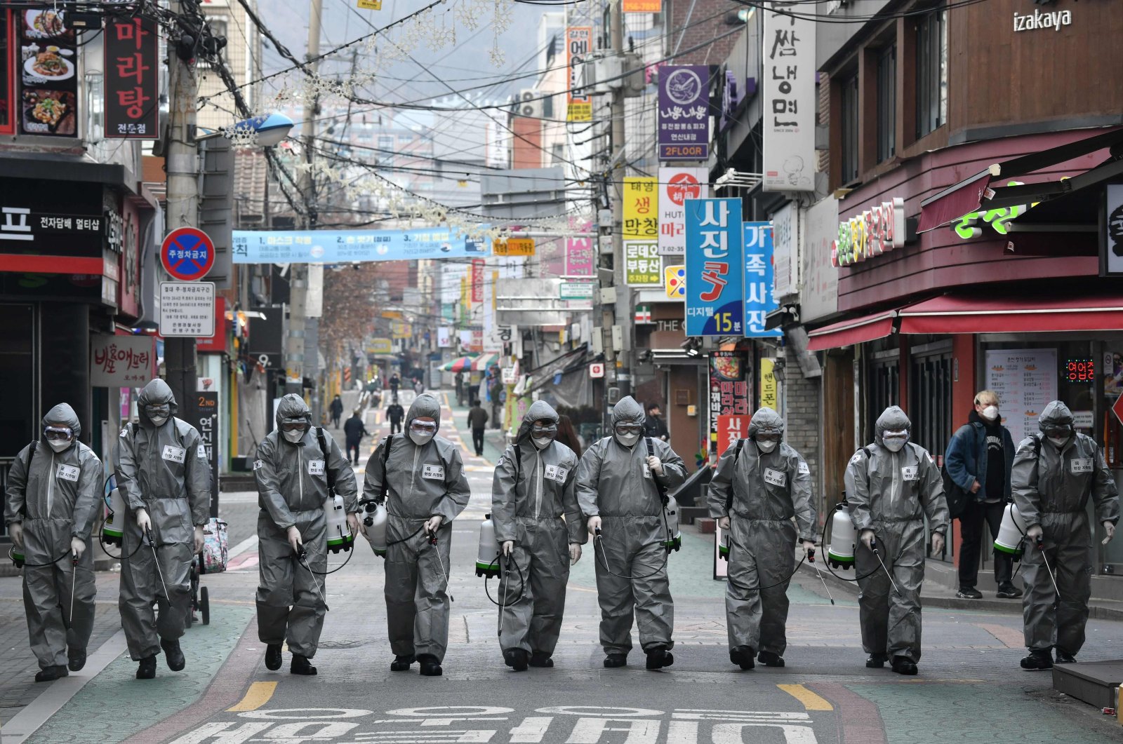 South Korean soldiers wearing protective gear spray disinfectant to help prevent the spread of the COVID-19 coronavirus, at a shopping district in Seoul, March 4, 2020. (AFP Photo)