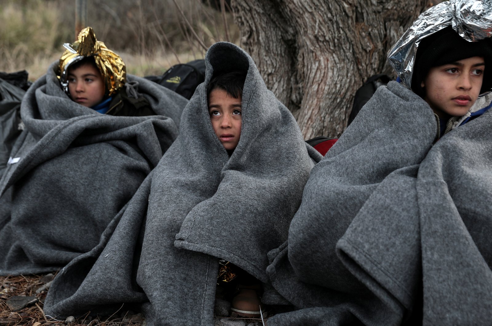 Children are covered with blankets and thermal blankets after migrants from Afghanistan arrived on a dinghy on a beach near the village of Skala Sikamias on the island of Lesbos, Feb. 28, 2020. REUTERS