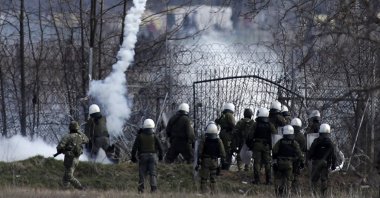 Greek police guard as migrants gather at a border fence on the Turkish side, during clashes at the Greek-Turkish border in Kastanies, Evros region on March 7. Thousands of refugees and other migrants have been trying to get into EU member Greece in the past week after Turkey declared that its previously guarded borders with Europe were open. (AP Photo)