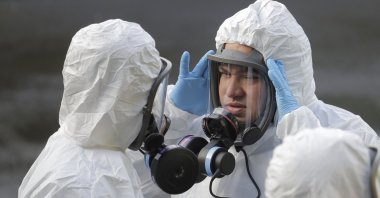 A worker from a Servpro disaster recovery team wearing a protective suit and respirator adjusts his mask before entering the Life Care Center in Kirkland, Wash. to begin cleaning and disinfecting the facility, Wednesday, March 11, 2020, near Seattle. The nursing home is at the center of the outbreak of the COVID-19 coronavirus in Washington state. (AP Photo)