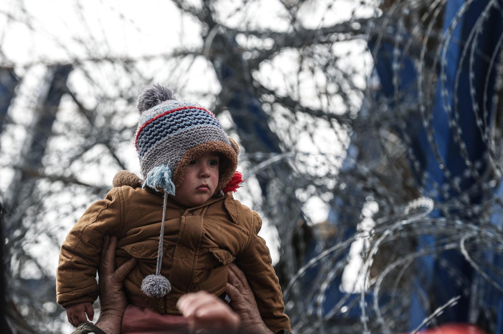 A child is seen waiting in front of wire ropes at the Turkish-Greek border. On the 13th day since asylum-seekers, refugees and other migrants started to gather at the Turkish-Greek border, the desperate wait for Europe to open its borders continues, March 8, 2020 (AA Photo)