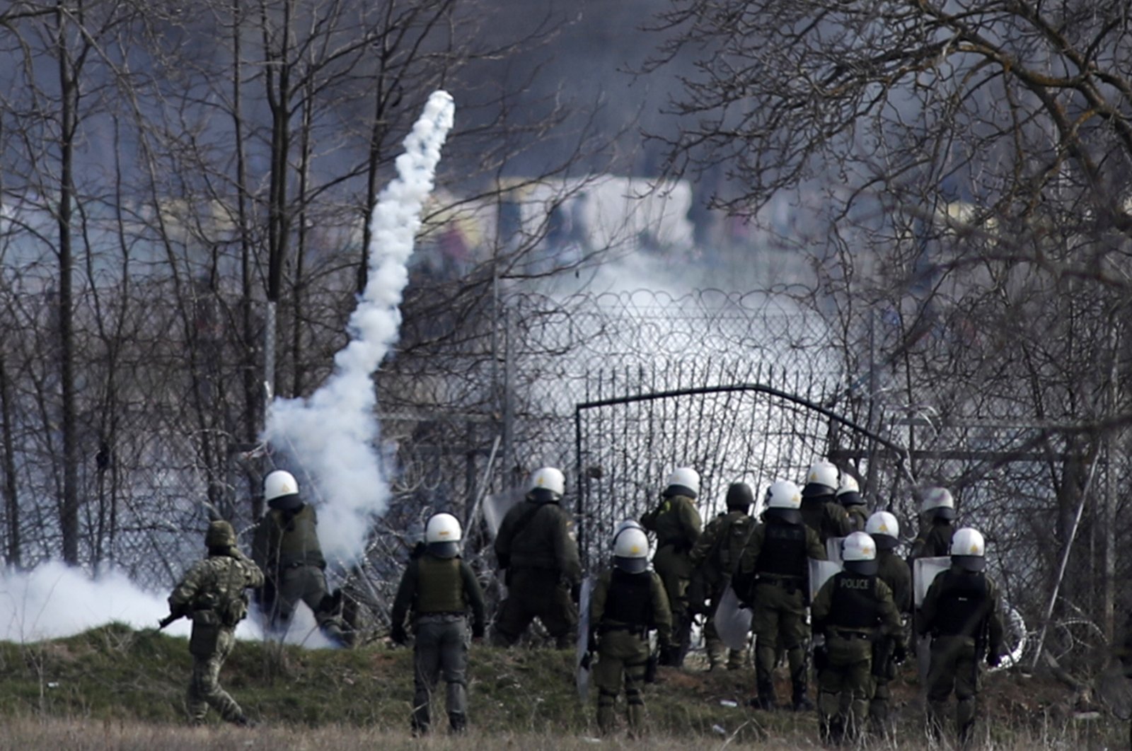 Greek police guard as migrants gather at a border fence on the Turkish side, during clashes at the Greek-Turkish border in Kastanies, Evros region on March 7. Thousands of refugees and other migrants have been trying to get into EU member Greece in the past week after Turkey declared that its previously guarded borders with Europe were open. (AP Photo)