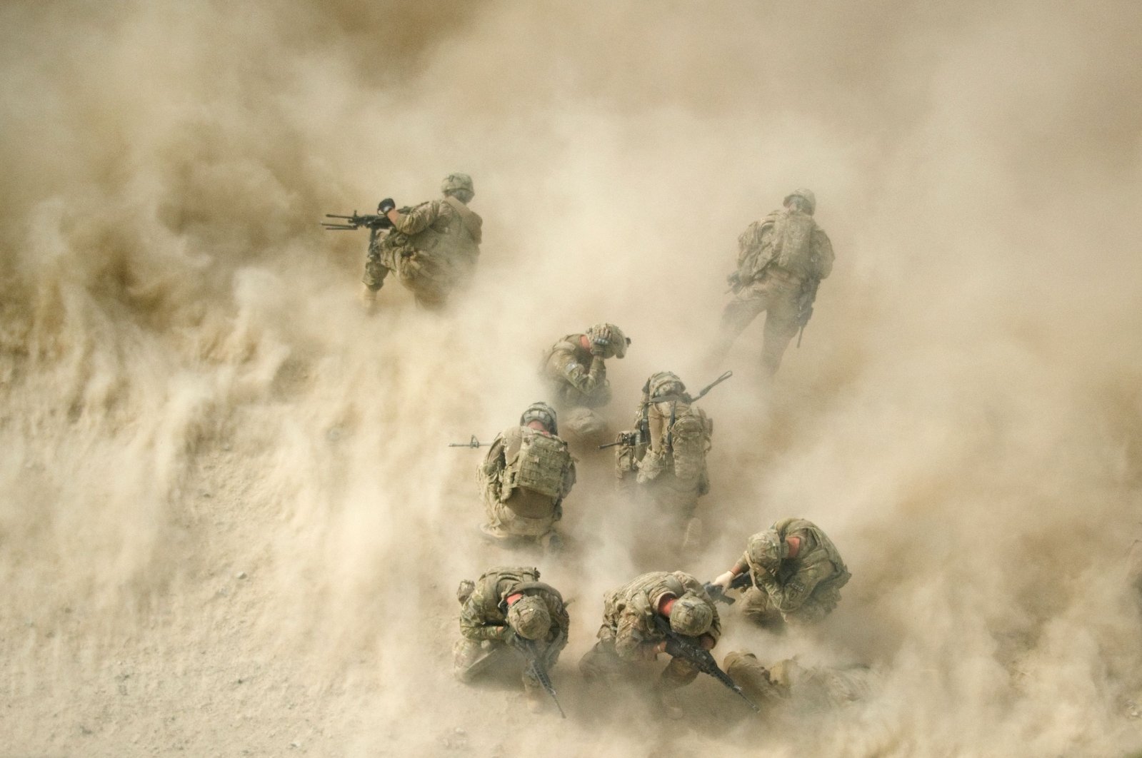 U.S. soldiers gather near a destroyed vehicle and protect their faces from rotor wash, as their wounded comrades are airlifted by a Medevac helicopter from the 159th Brigade Task Force Thunder to Kandahar Hospital Role 3, Aug. 23, 2011. (AFP Photo)