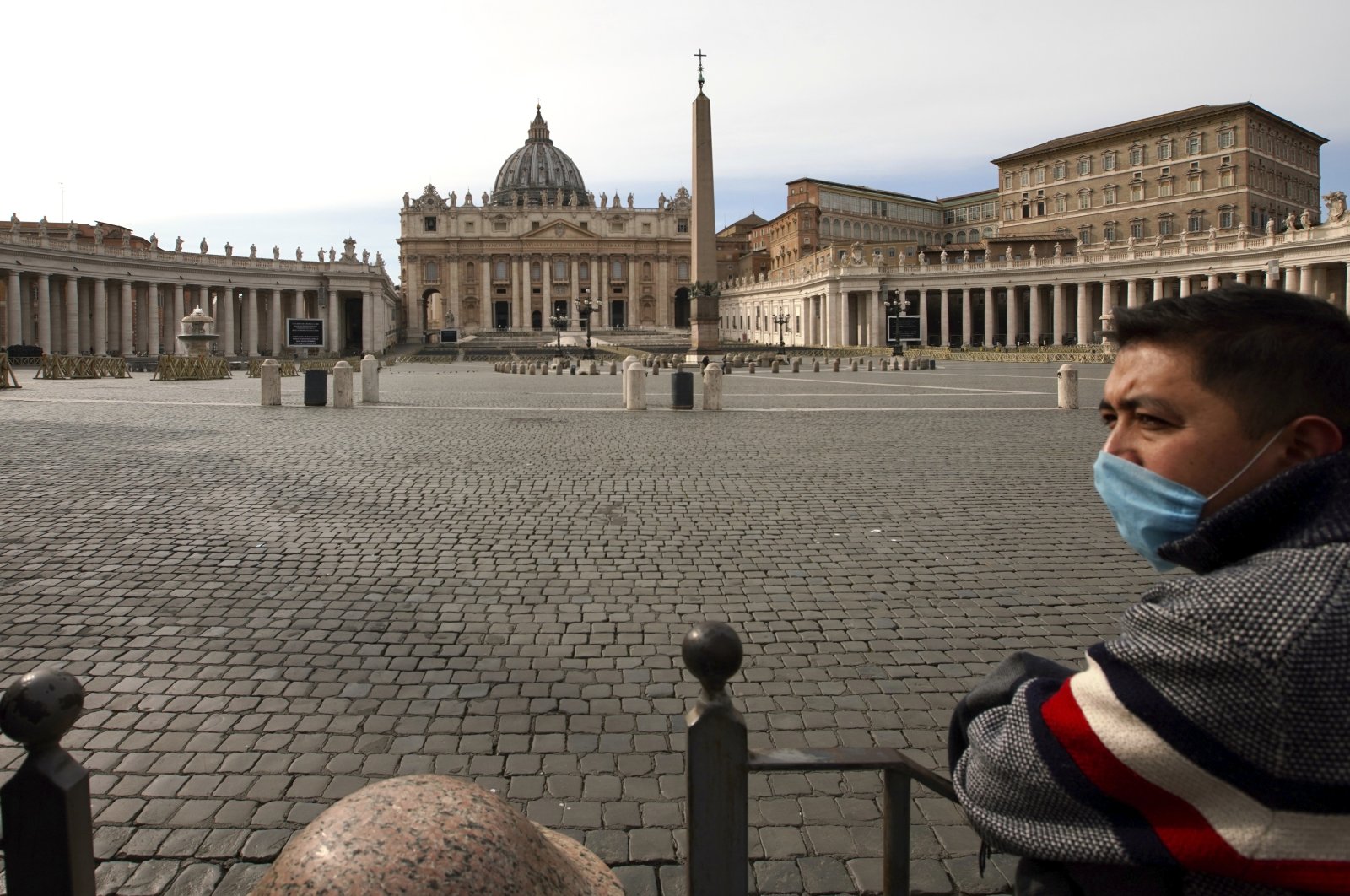 A man wears a mask as he looks at an empty St. Peter's Square after the Vatican erected a new barricade at the edge of the square, in Rome, Tuesday, March 10, 2020. (AP Photo)