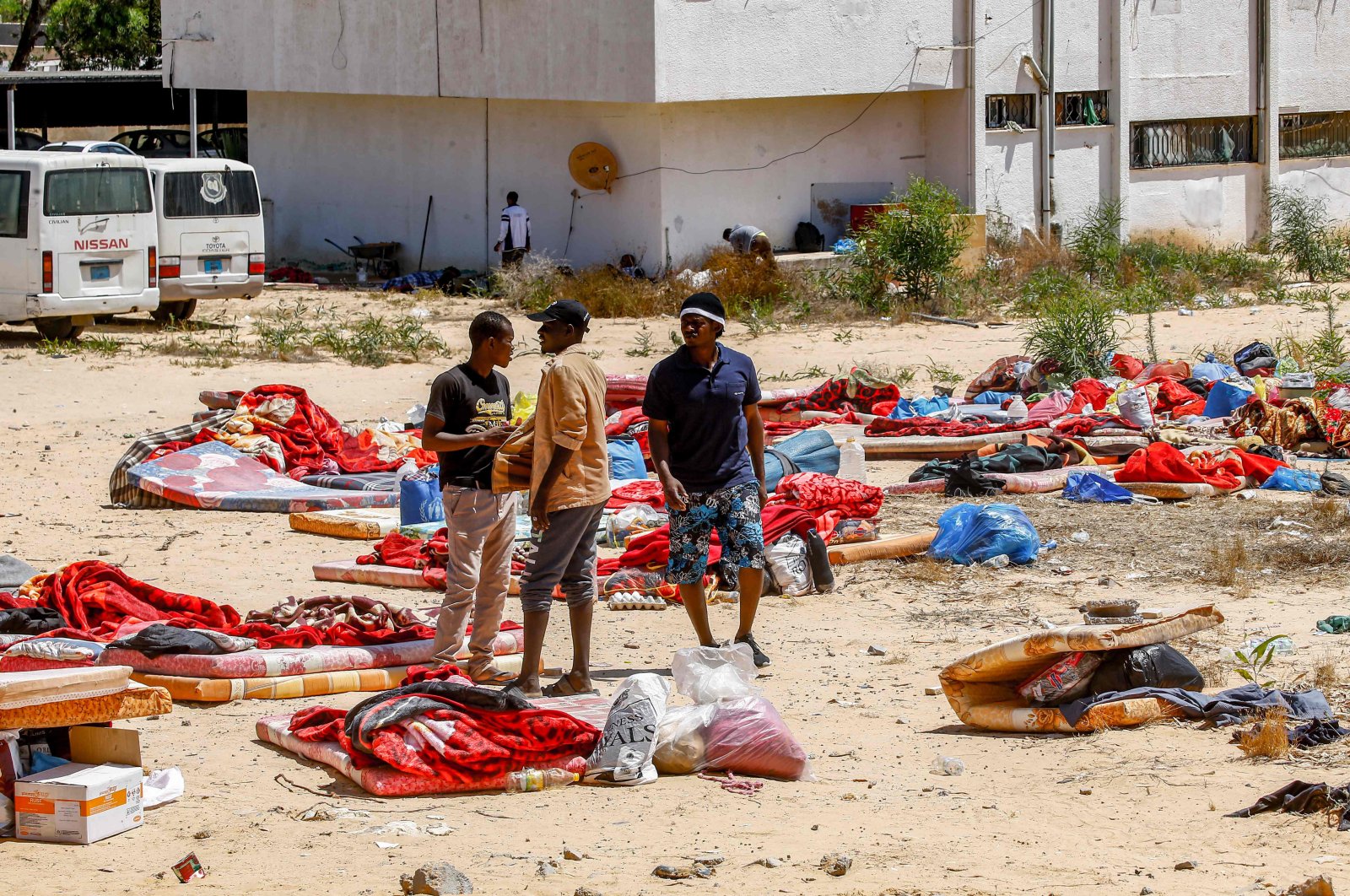 Migrants stand and walk outside at a detention centre used by the Libyan Government of National Accord (GNA) in the capital Tripoli's southern suburb of Tajoura on July 3, 2019, following an airstrike on a nearby building that left dozens killed the previous night. (AFP Photo)