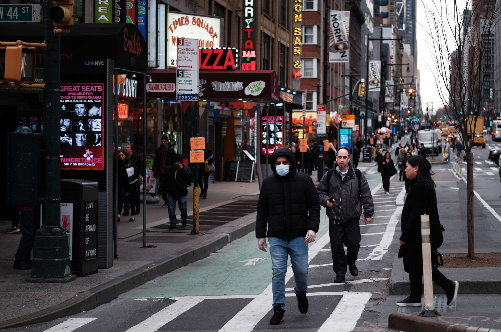 People walk near the Theater District in Manhattan on March 12 in New York City. New York City's Broadway theaters will need to close by 5 p.m. Thursday after New York Gov. Andrew Cuomo announced a ban on gatherings of 500 people or more amid the growing coronavirus outbreak. (AFP Photo)