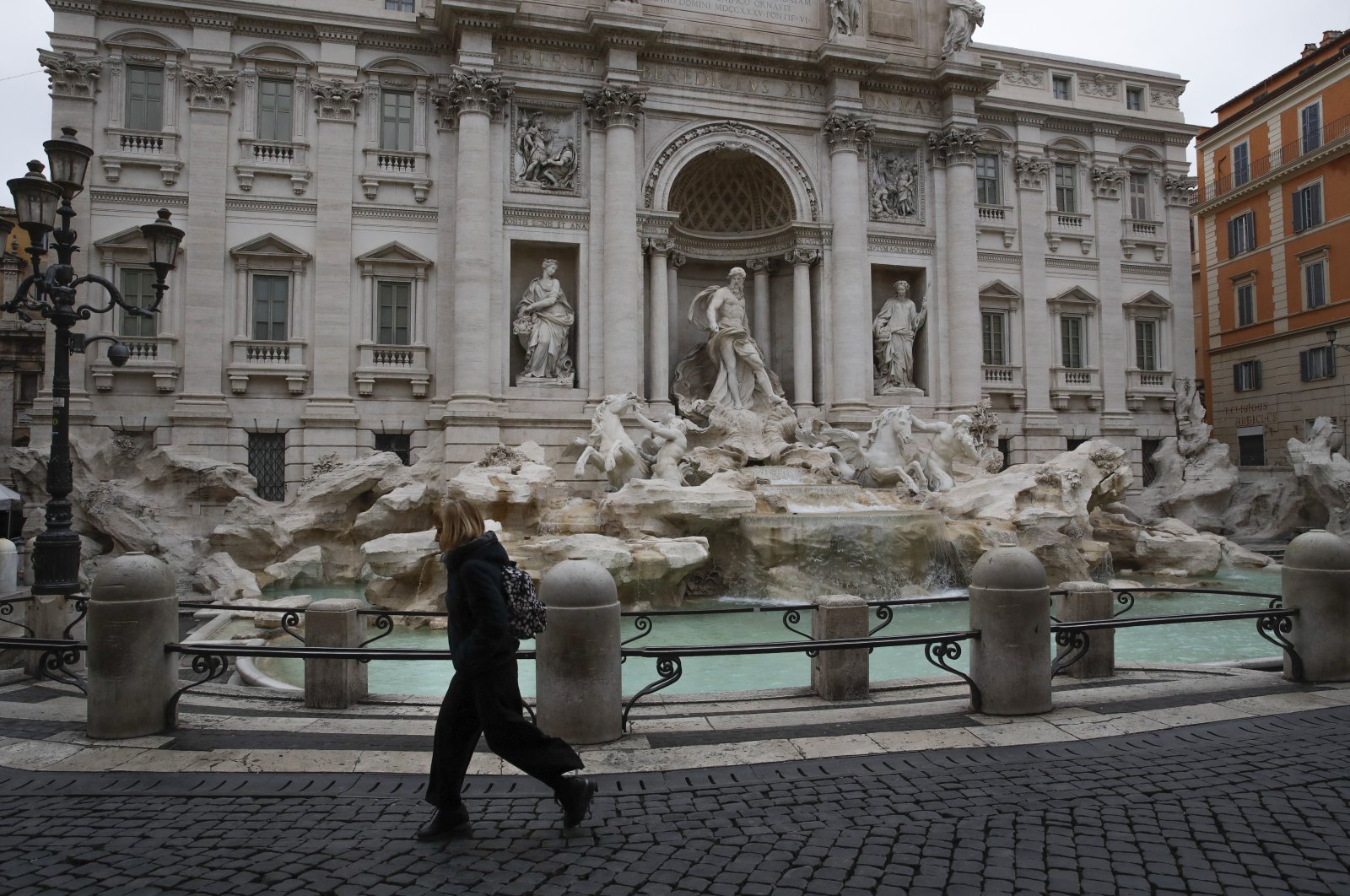 A woman walks past the Trevi fountain in Rome, Friday, March 13, 2020. (AP Photo)