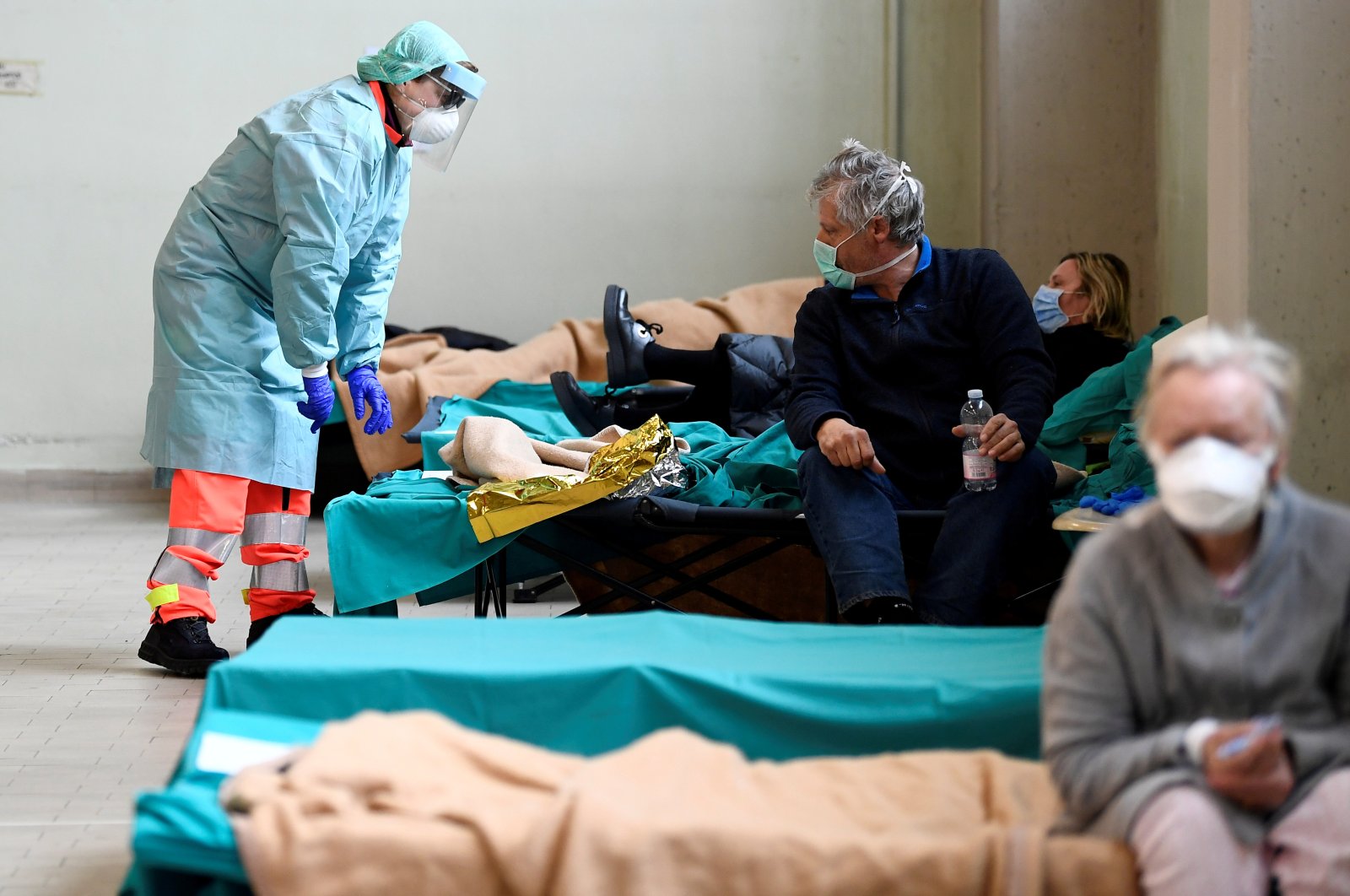 Medical personnel wearing protective face masks help patients inside the Spedali Civili hospital in Brescia, Italy March 13. (Reuters Photo)