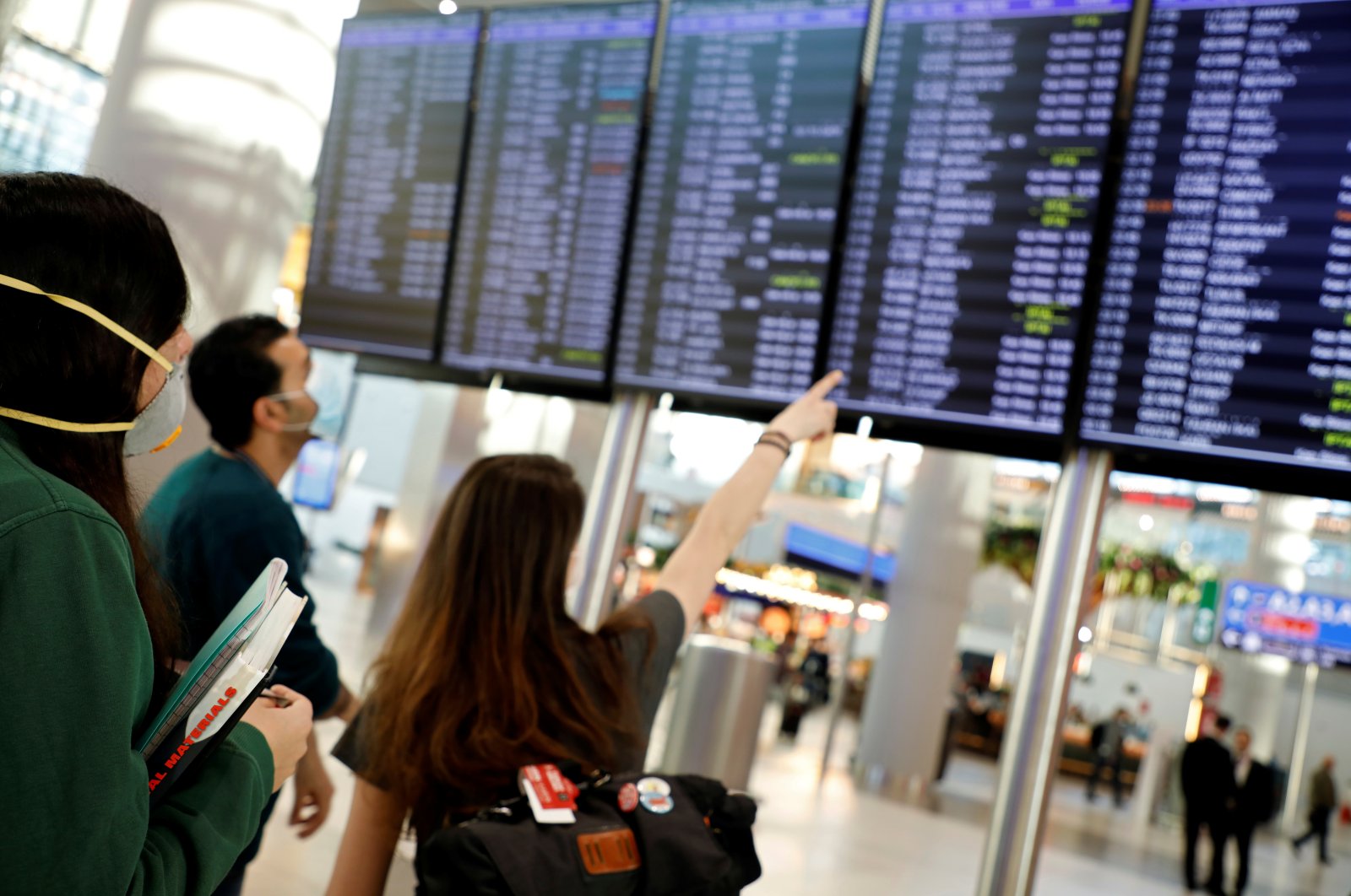 People, wearing protective face masks to protect against the coronavirus, look at flight status information at Istanbul Airport, Friday, March 13, 2020. (Reuters Photo)