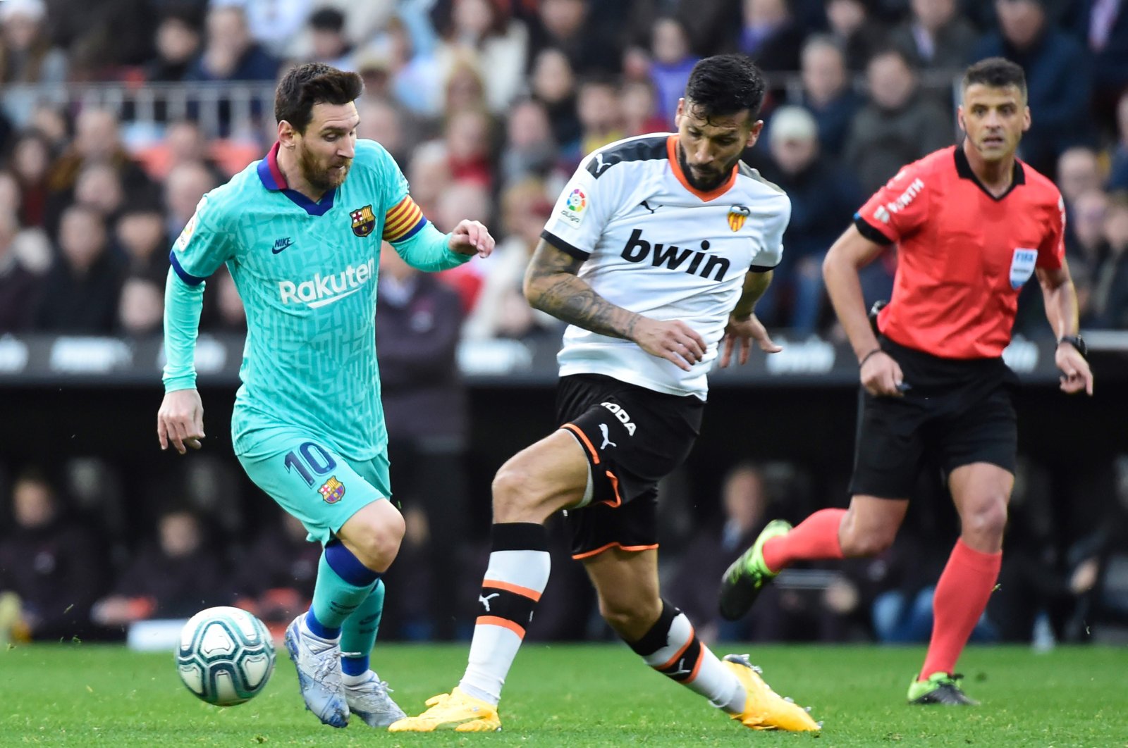 Ezequiel Garay (C) challenges Barcelona's Lionel Messi(L), Valencia, Jan. 25, 2020. (AFP Photo)