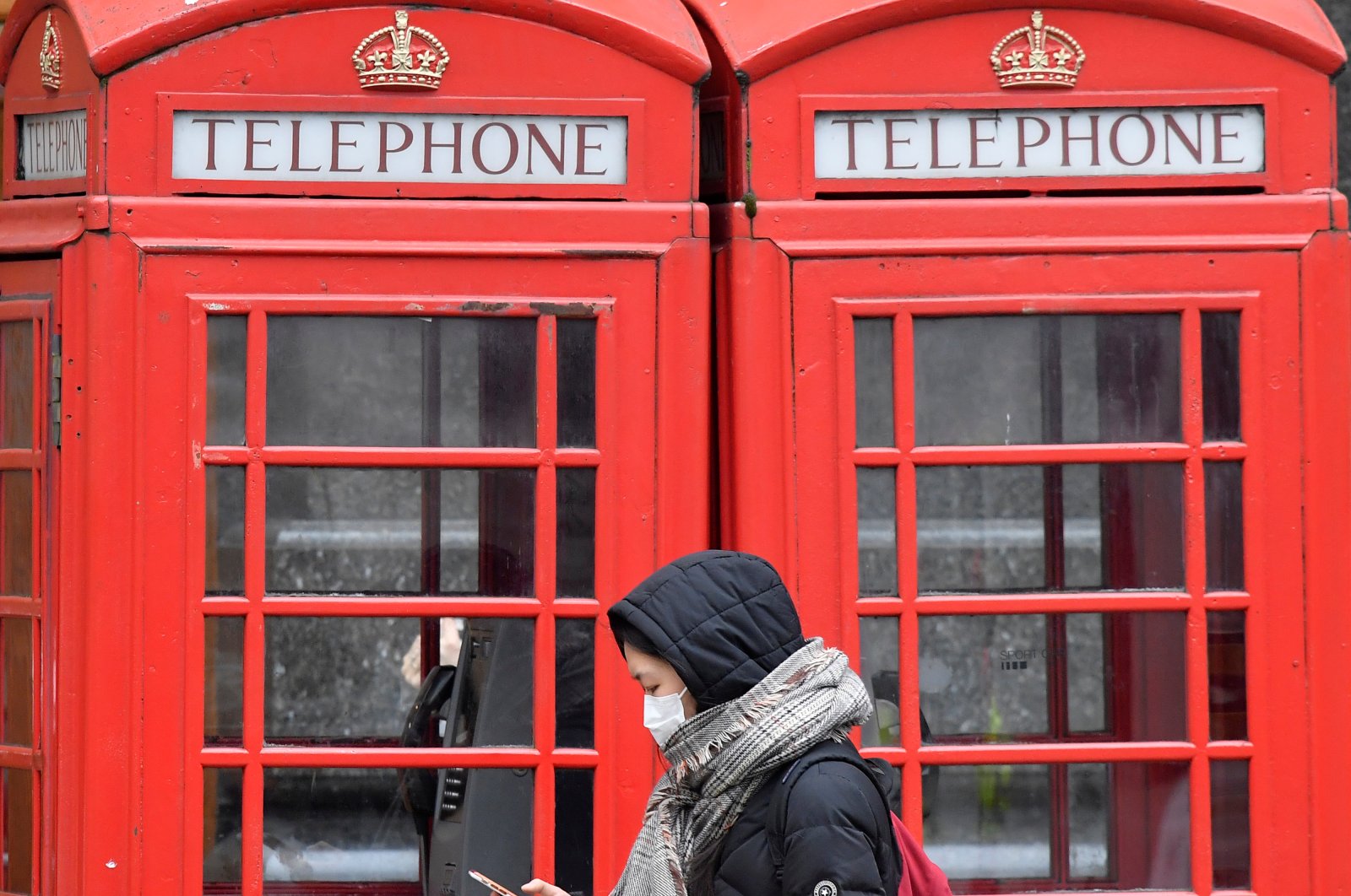 A woman in a protective face mask walks past traditional red telephone boxes, as the number of coronavirus (COVID-19) cases grows around the world, London, Britain, March 15, 2020. (Reuters Photo)