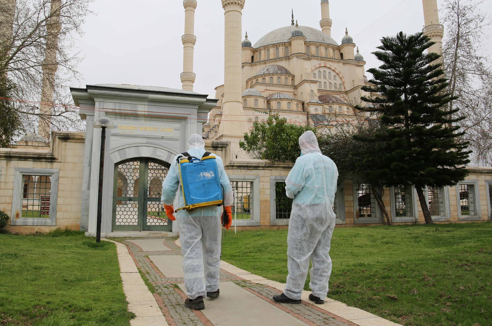 Men wearing protective suits spray disinfectant at a mosque amid the spread of the coronavirus (COVID-19) in Adana, March 12, 2020. (Photo by İHA)