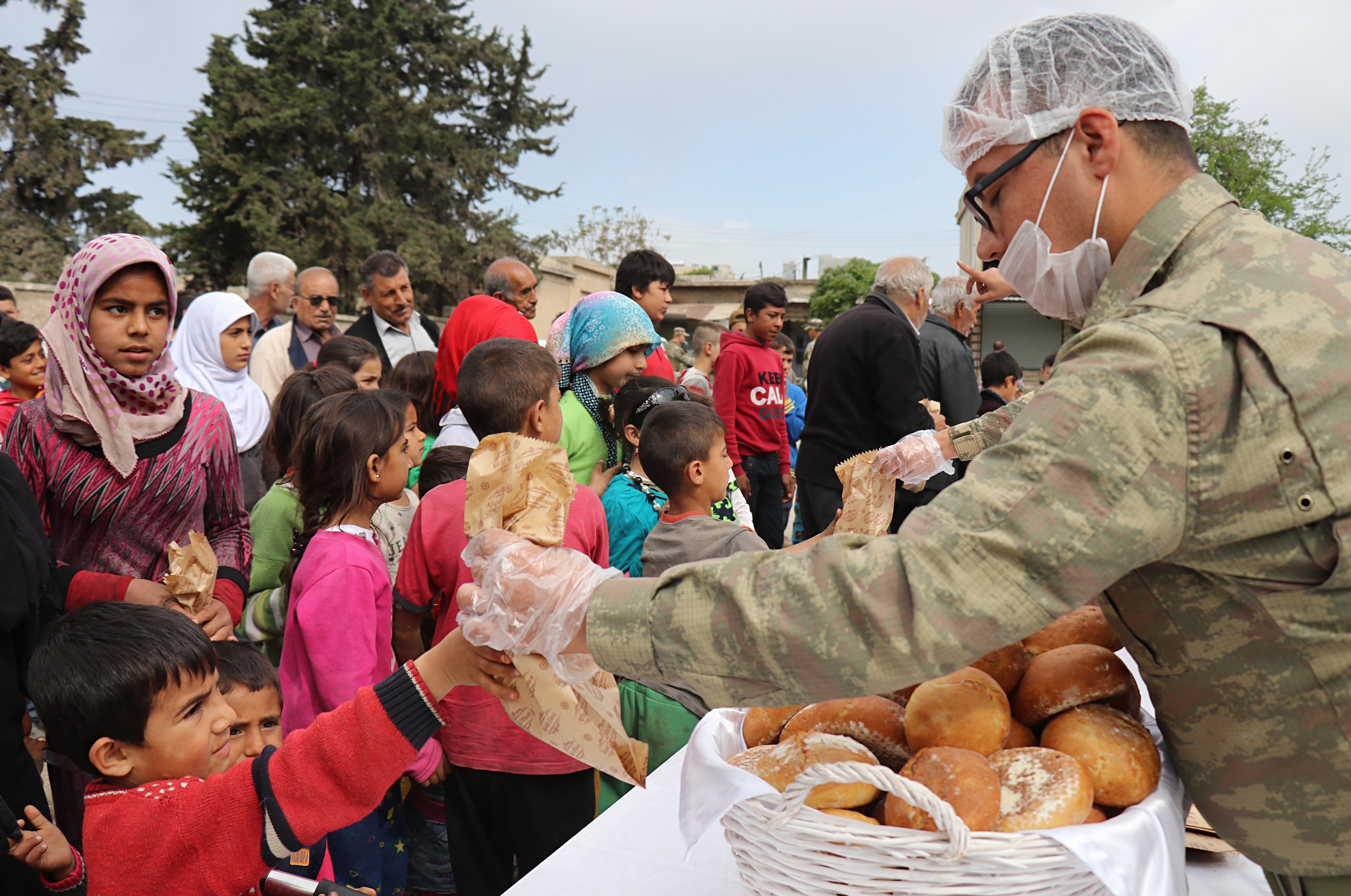 A Turkish soldier distributes bread to Afrin locals after Operation Olive Branch. (AA)