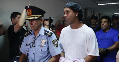 Former football star Ronaldinho is escorted by police officers to declare to judge Clara Ruiz Diaz at Justice Palace in Asuncion, Paraguay, Saturday, March 7, 2020. (AP Photo)