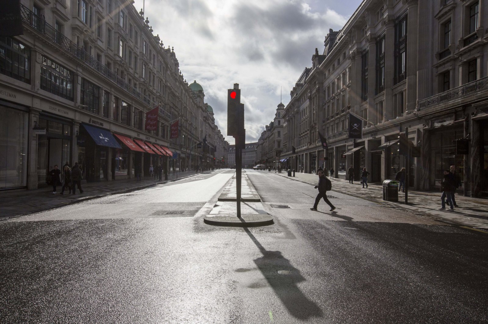 A few people stroll along a main shopping street at Regent Street, London, Saturday, March 14, 2020. (AP Photo)