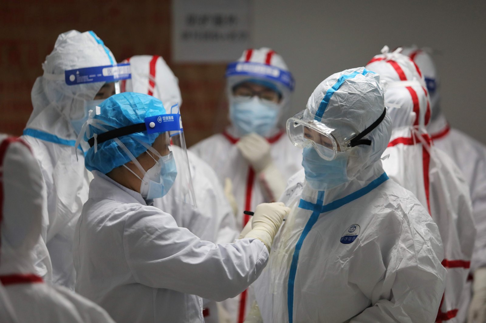 Medical staff write messages on their protective suits before attending to COVID-19 coronavirus patients at the Red Cross Hospital, Wuhan, March 16, 2020. (AFP Photo)