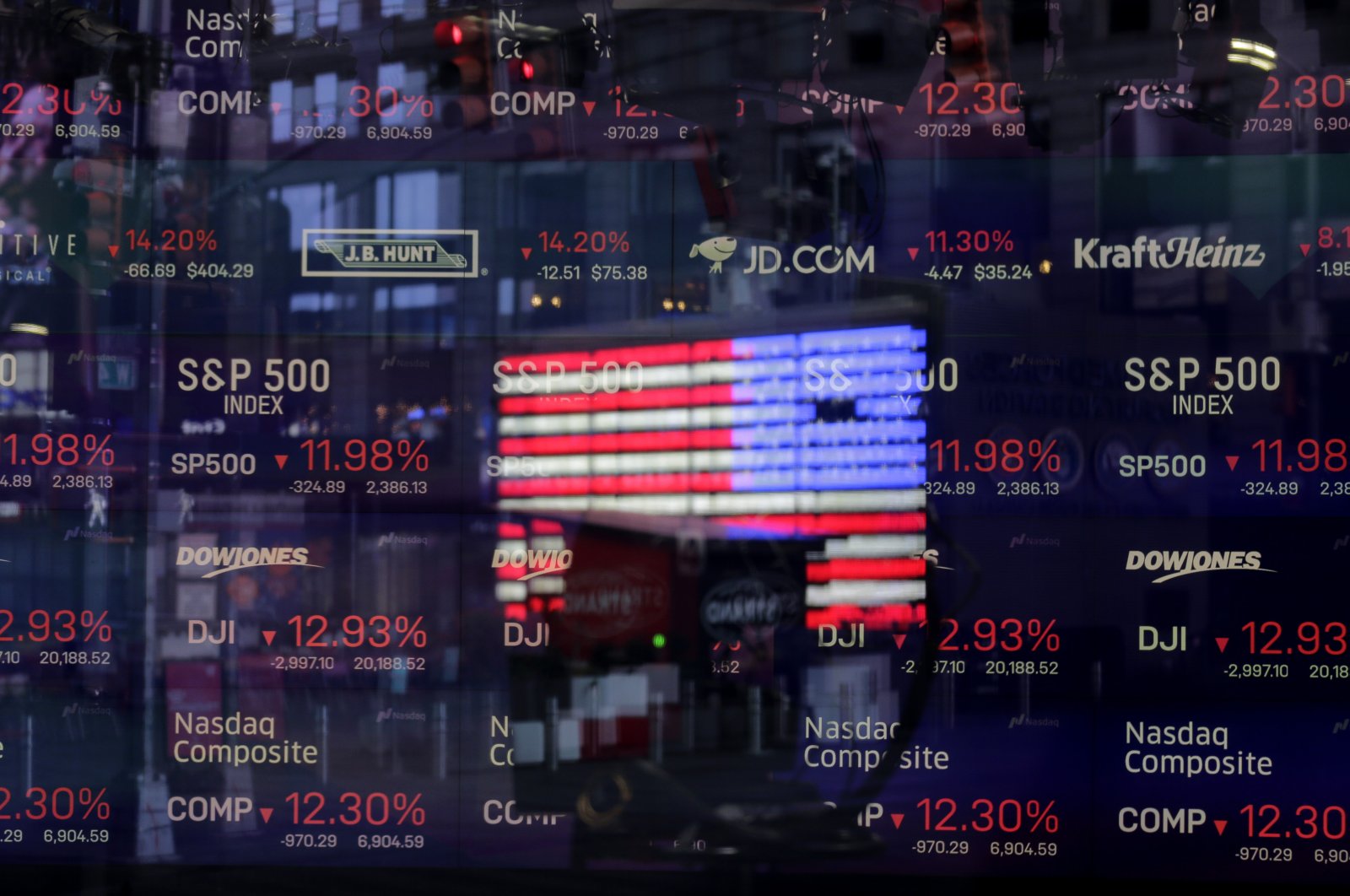 A United States flag is reflected in the window of the Nasdaq studio, which displays indices and stocks down, in Times Square, New York, Monday, March 16, 2020. (AP Photo)