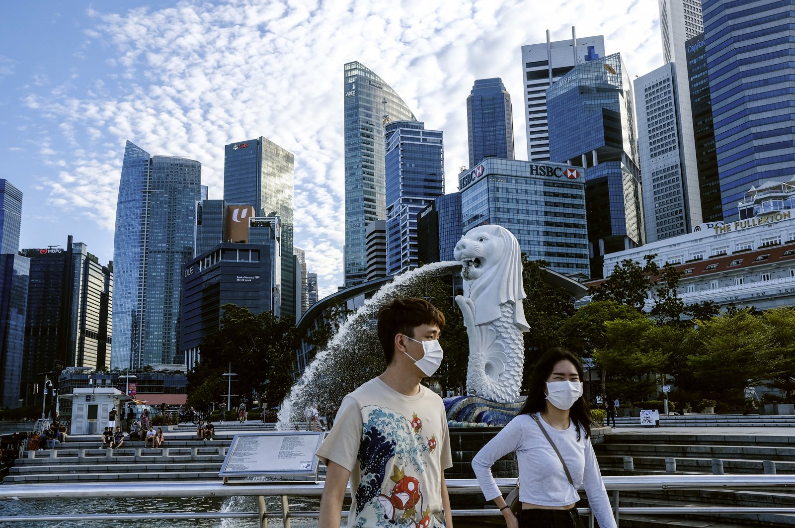 A couple wearing face masks walk past the Merlion statue in Singapore, Saturday, March 14, 2020. (AP Photo)