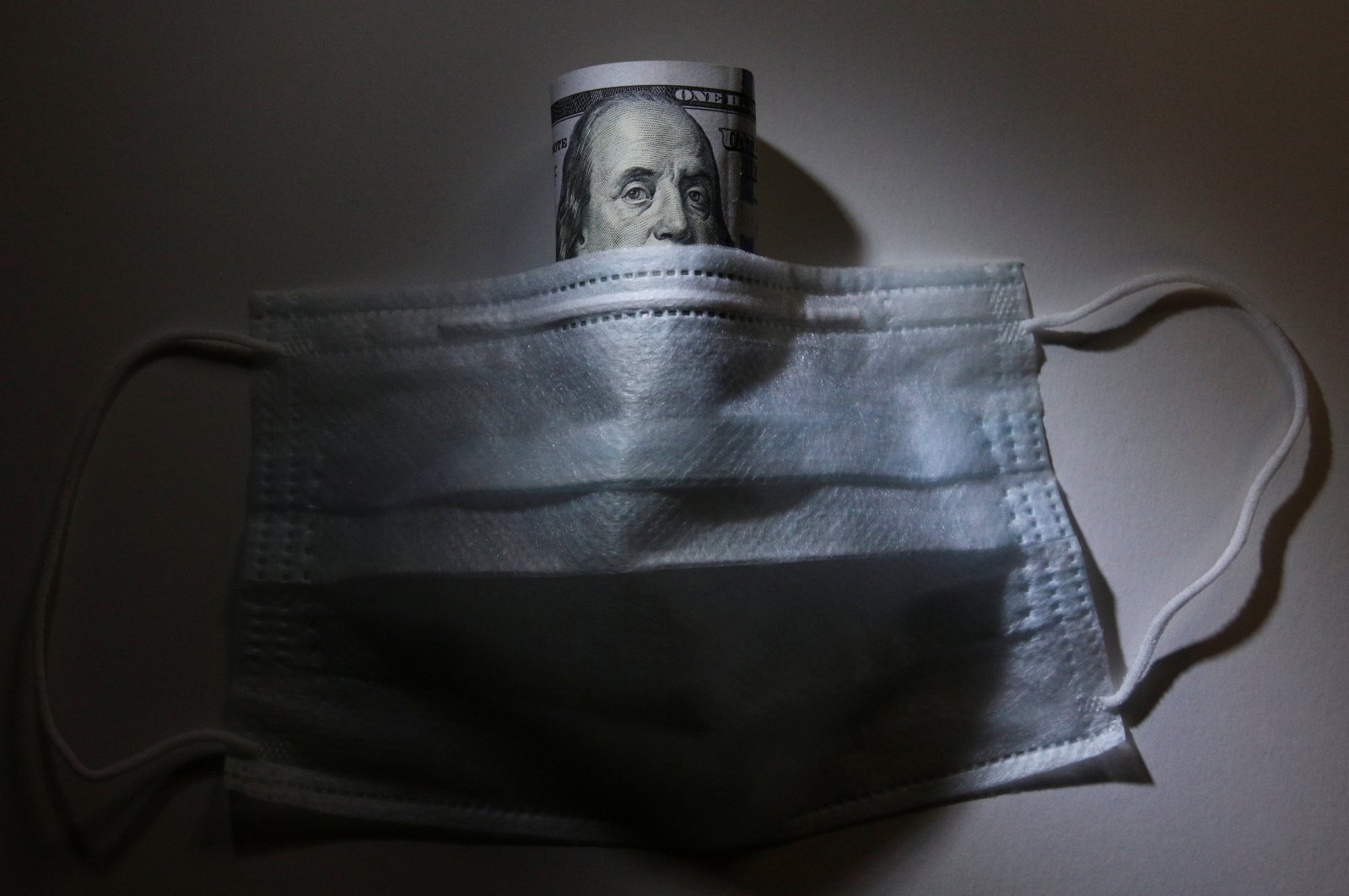 A U.S. dollar banknote is pictured behind a protective mask, a widely used preventive measure against the coronavirus, in this illustration taken Tuesday, March 17, 2020. (Reuters Photo)