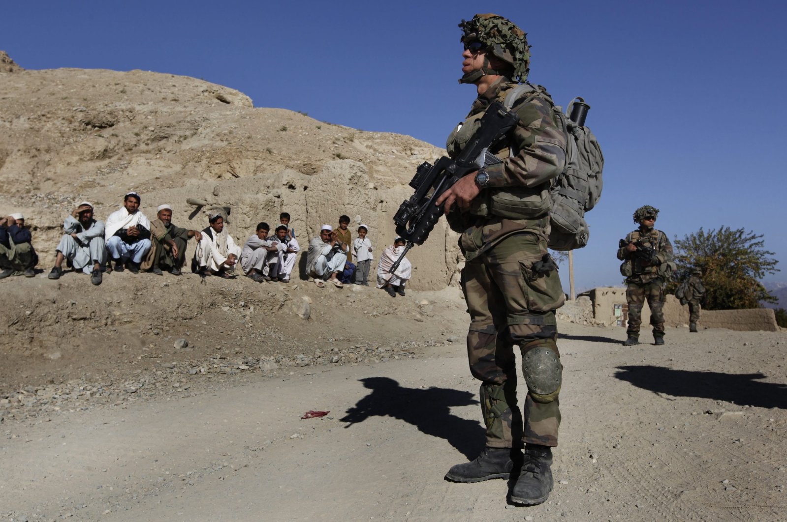 NATO soldiers patrol as Afghan men look on during an operation in the Tagab Valley, Nov. 15, 2009. (AP Photo)