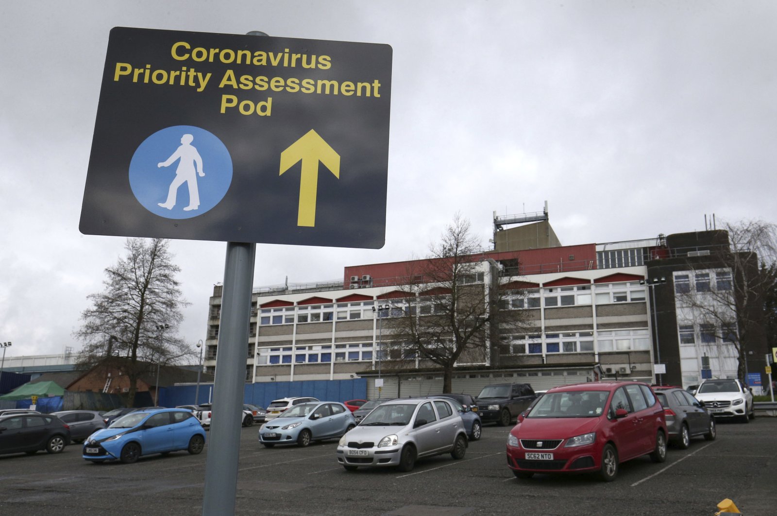 A sign outside Watford General Hospital directing potential patients to the newly set up coronavirus assessment area, London, Saturday, March 14, 2020. (AP Photo)