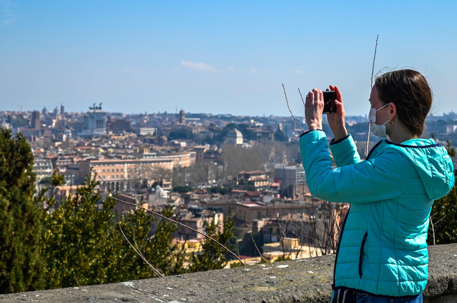 A woman wearing a face mask takes a photo of Rome from the Gianicolo terrace on March 18, during the country's lockdown within the new coronavirus crisis. (AFP Photo)