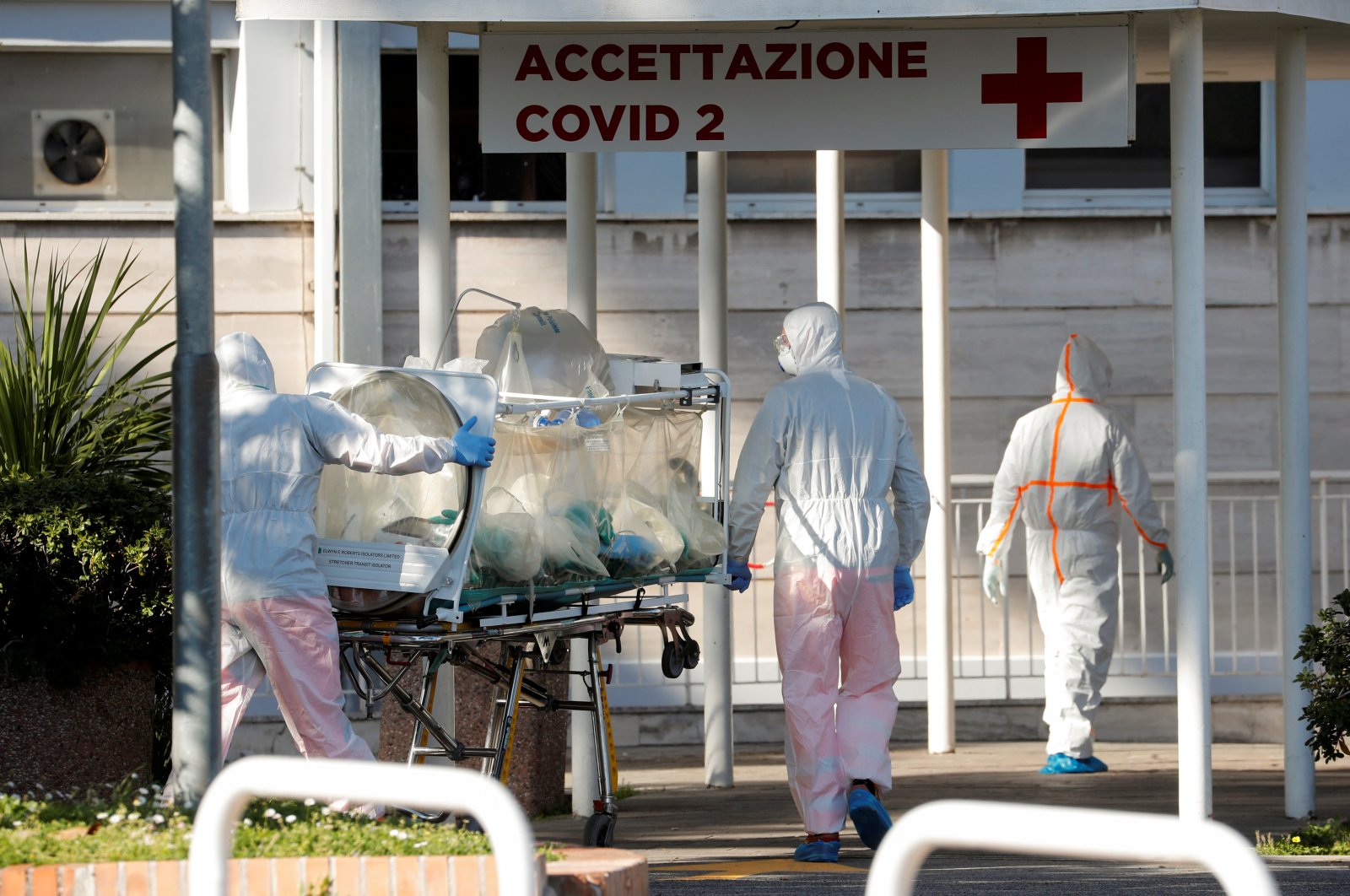 Medical workers in protective suits push an isolation stretcher in front of the Columbus Clinic, where patients suffering from coronavirus disease (COVID-19) were moved from Spallanzani Hospital, in Rome, March 16, 2020. (Reuters Photo)
