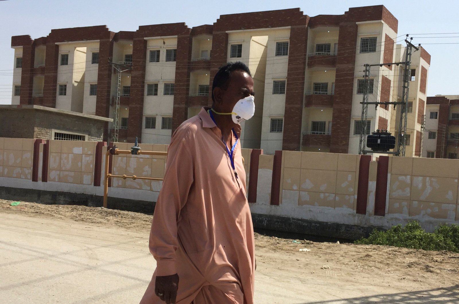 A man wears a protective mask following an outbreak of the coronavirus disease (COVID-19), as he walks in front of buildings, declared by the government as quarantine for the suspected pilgrims, who crossed Taftan border post with Iran, in Sukkur, Pakistan March 18. (Reuters Photo)