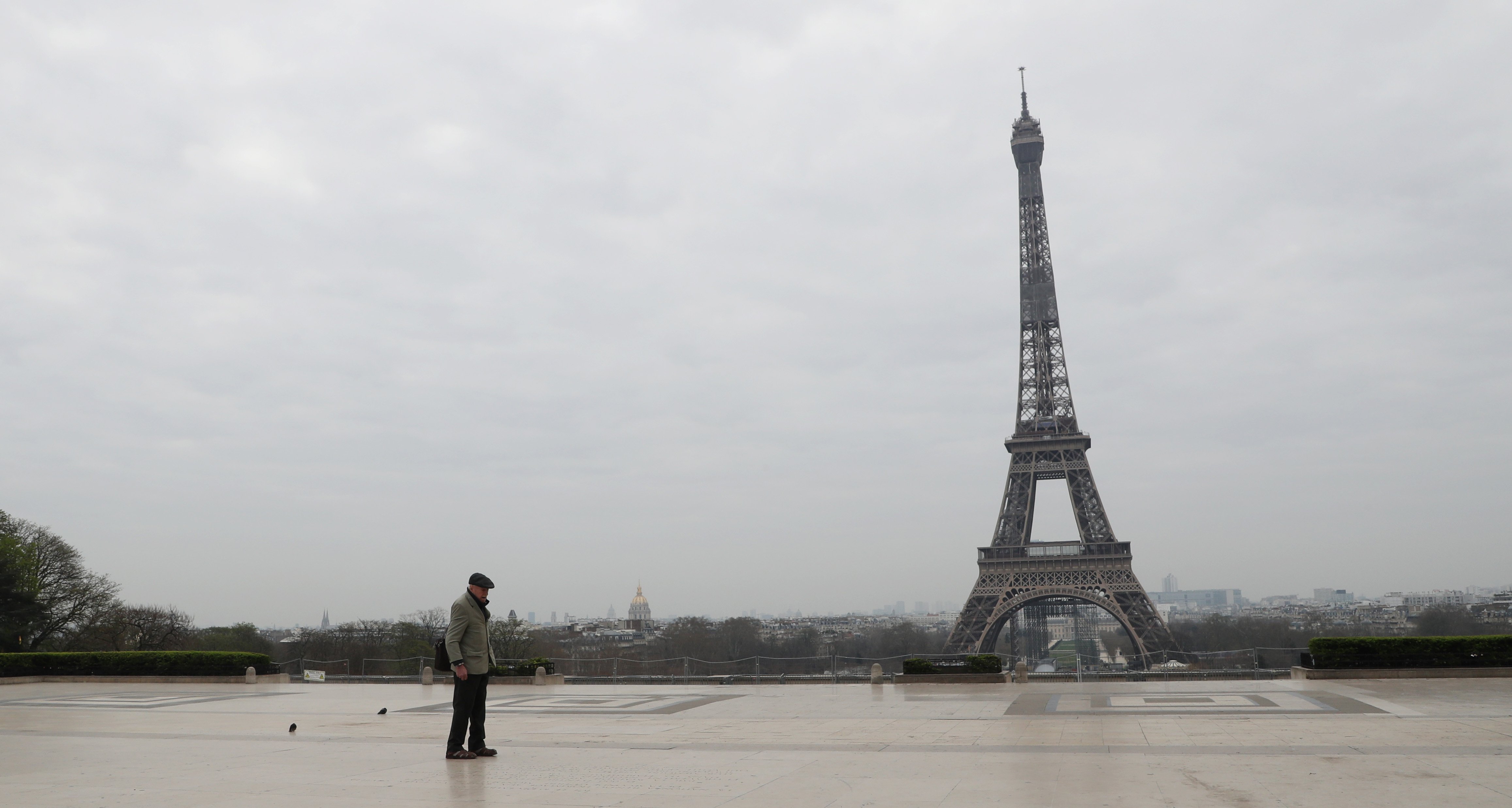 An elderly man walks by the Esplanade du Trocadero square near the Eiffel Tower in Paris, on March 18, 2020 in Paris as a strict lockdown comes into in effect in France to stop the spread of COVID-19, caused by the novel coronavirus. - (Photo by Ludovic Marin / AFP)
