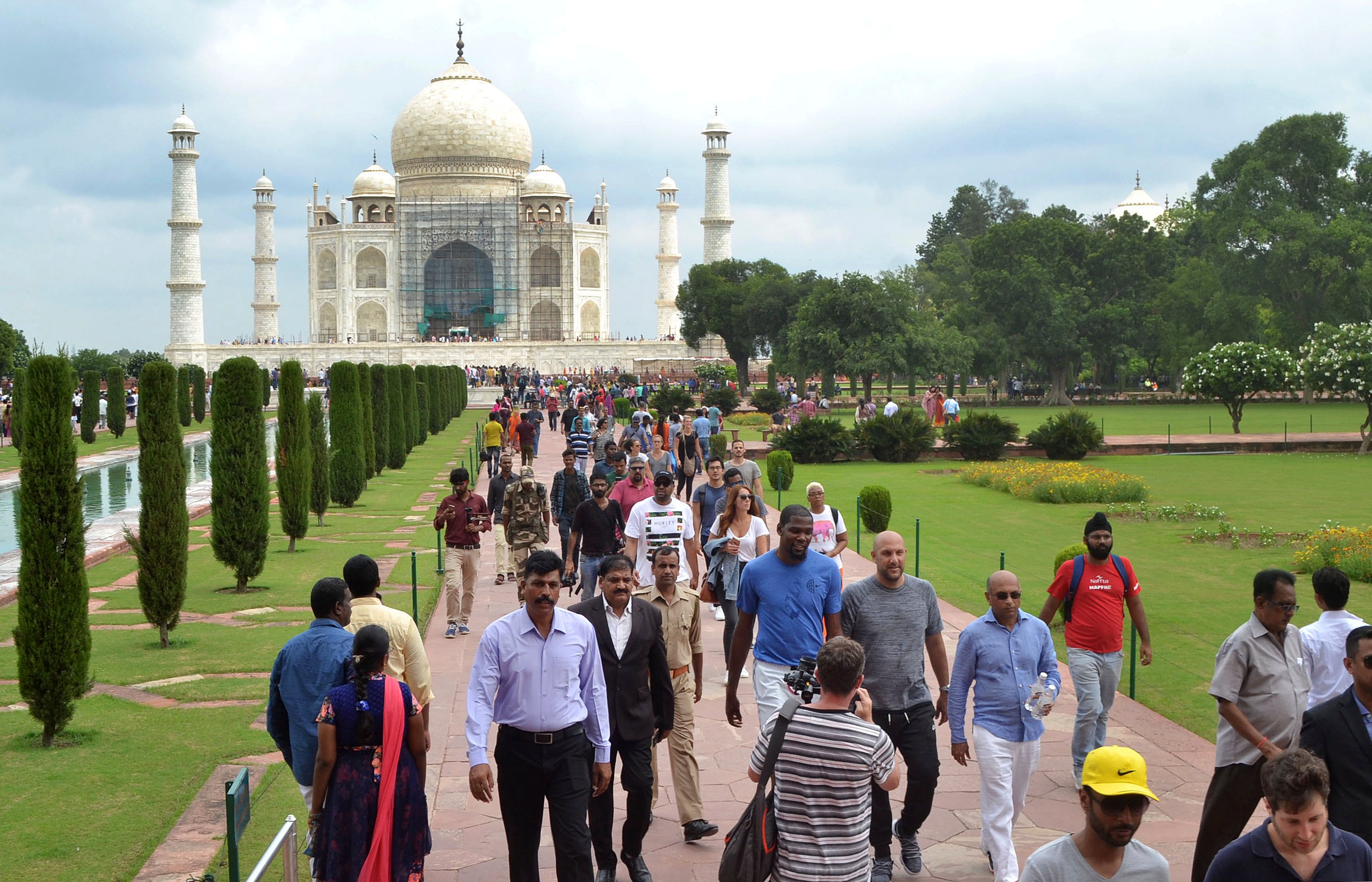 NBA basketball player Kevin Durant, center in blue t-shirt, walks in front of Taj Mahal in Agra, India, Saturday, July 29, 2017. Durant is in India to support the continued growth of basketball in the country and meet the elite prospects of NBA Academy India. (AP Photo/Pawan Sharma)