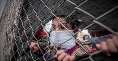 Syrian children wearing face masks look on in a camp near the Turkey-Syria border. (AA Photo)