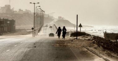 Two women walk along the sea front as heavy winds blow dust and sand across a main road in occupied Gaza City, Jan. 6, 2019. (AFP Photo)