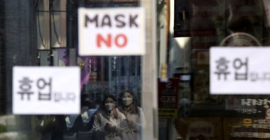 Women wearing a face mask are reflected on a window of a temporarily closed store in Seoul, South Korea, Wednesday, March 18, 2020. (AP Photo)