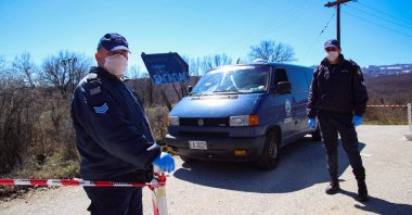 This file photo shows Greek policemen wearing face masks as a protective measure standing guard at a checkpoint on the road to the village of Dragasia near Kozani on Tuesday, March 17, 2020. (AFP Photo)