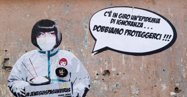 A mural against xenophobia towards Chinese people is seen after two cases of the coronavirus were confirmed in Italy, by street artist Laika in Rome, Feb. 5, 2020. The mural shows a Chinese woman wearing a protective mask with text reading "#JeNeSuisPasUnVirus" next to words on the wall that read: "There is an epidemic of ignorance around, we need to protect ourselves." REUTERS