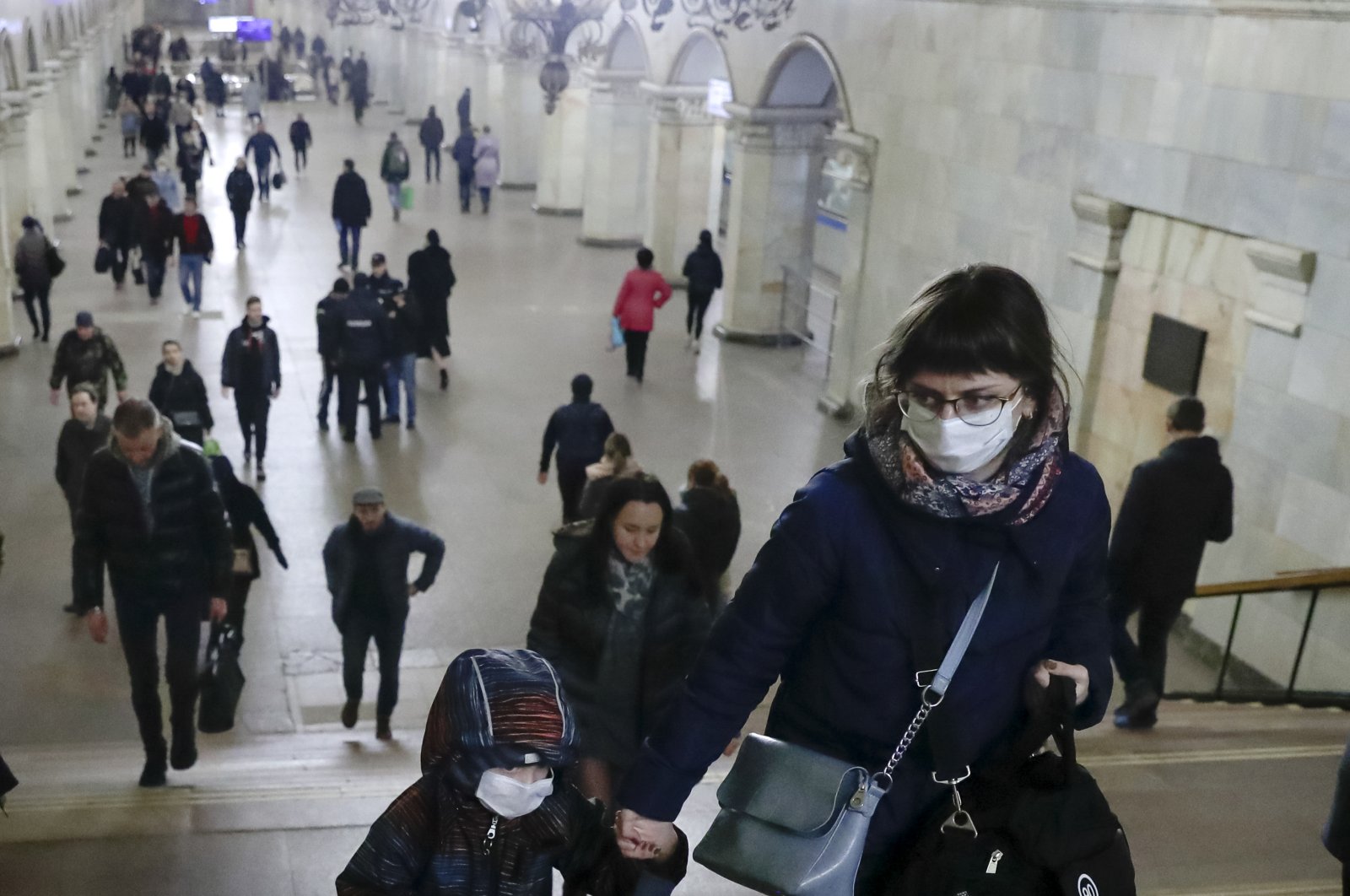 A woman with her child wear medical masks walk inside the Komsomolskaya Metro station, Moscow, March 18, 2020. (AP Photo)
