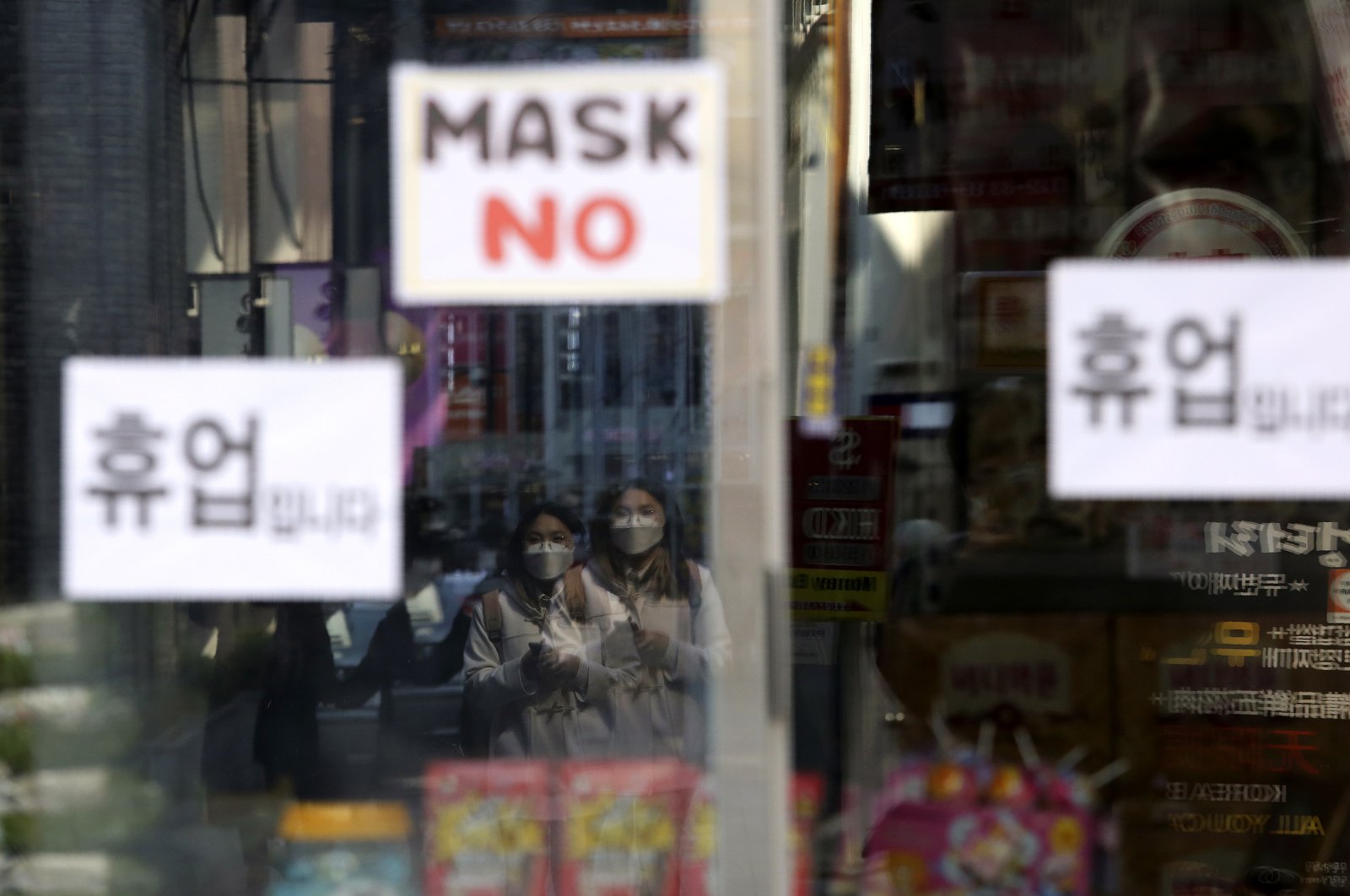 Women wearing a face mask are reflected on a window of a temporarily closed store in Seoul, South Korea, Wednesday, March 18, 2020. (AP Photo)