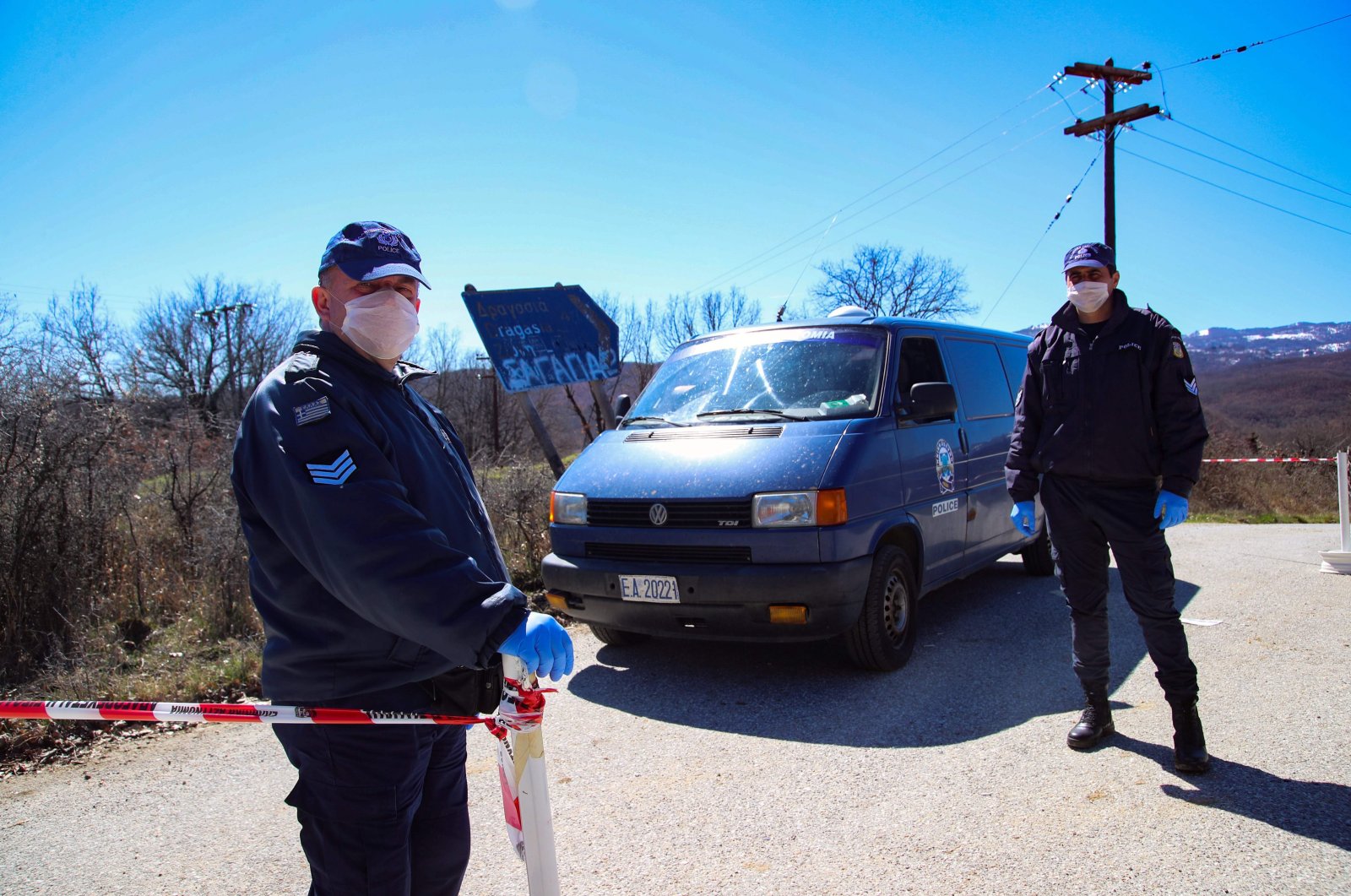 This file photo shows Greek policemen wearing face masks as a protective measure standing guard at a checkpoint on the road to the village of Dragasia near Kozani on Tuesday, March 17, 2020. (AFP Photo)