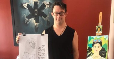 Mustafa Olcaytu Tuncel shows one of the painting he has done, Thursday, March 19, 2020, in Ankara. (AA Photo) 