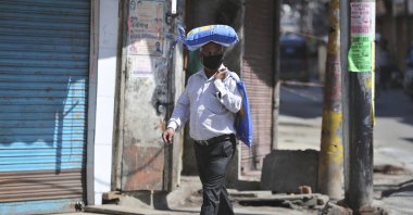 An Indian man, wearing a protective mask as a precaution against coronavirus, carries a bag of rice on his head during restrictions, Jammu, Friday, March 20, 2020. (AP Photo)