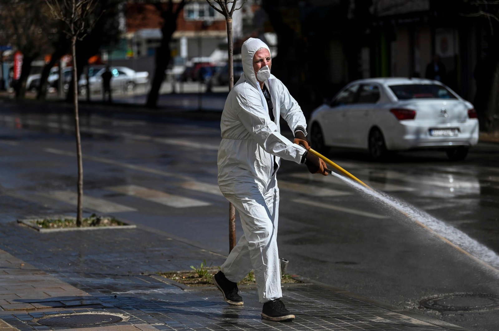 A municipality worker disinfects a street in Pristina, as part of measures to attempt to prevent the spread of the COVID-19 caused by the new Coronavirus, Tuesday, March 17, 2020. (AFP)