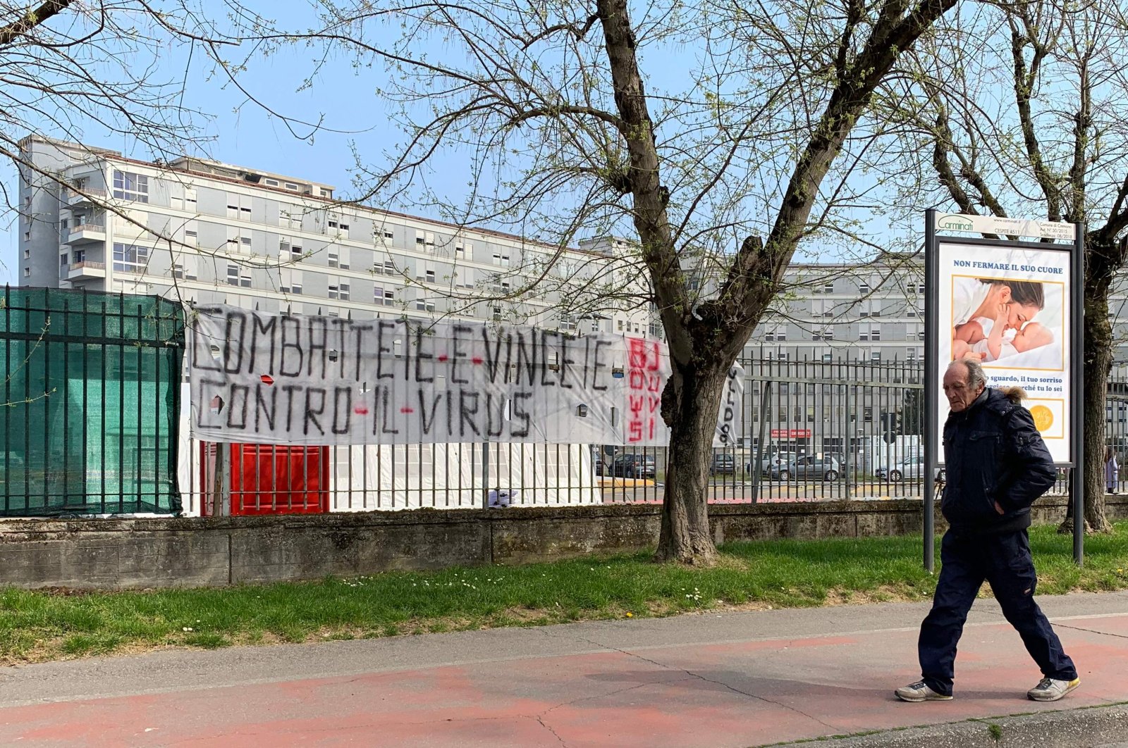 A man walks past a banner reading "fight and win against the virus," outside the hospital of Cremona, Milan, Friday, March 20, 2020. (AFP Photo)